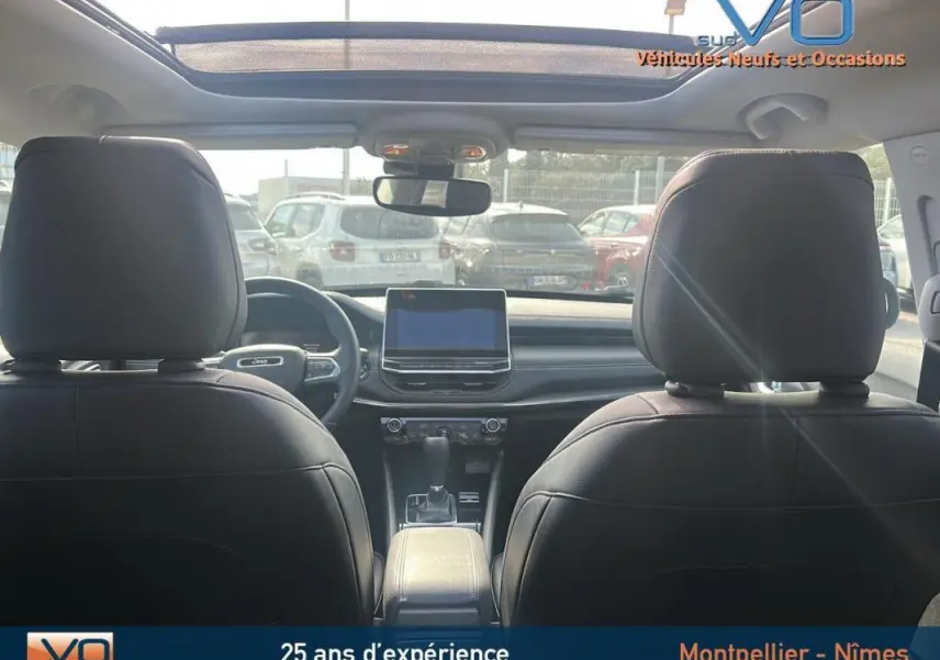 Vue intérieure arrière du Jeep Compass noir 2023 avec toit ouvrant panoramique et écran tactile central.