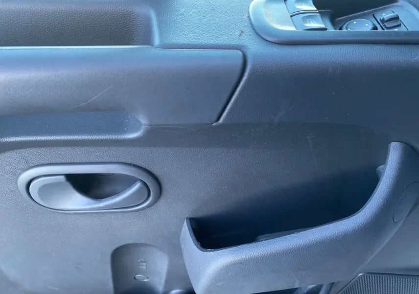 Poignée intérieure et commandes de lève-vitres côté conducteur du Renault Master Châssis Cabine 2023 en plastique noir.