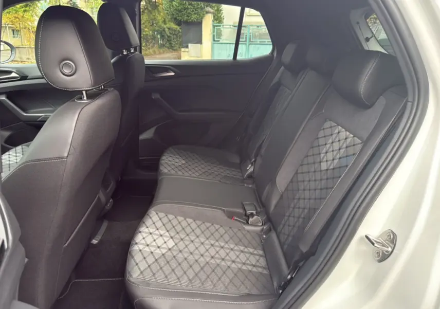 Vue latérale droite de l'intérieur arrière du Volkswagen T-Cross blanc avec sièges tissu à motif géométrique.