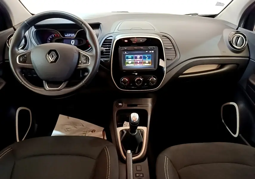 Vue intérieure avant du tableau de bord noir du Renault Captur Business TCe 90 avec écran tactile et volant cuir multifonctions.