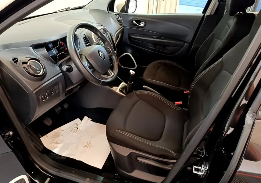 Vue intérieure côté conducteur du Renault Captur Business TCe 90 2018 noir, montrant sièges tissu et tableau de bord avec volant cuir.