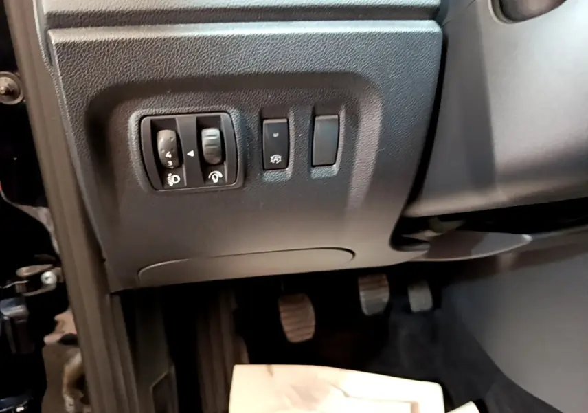 Gros plan sur les commandes de réglage des phares et autres boutons à gauche du volant dans le Renault Captur Business noir 2018.
