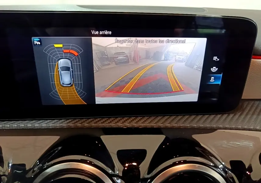 Écran tactile intérieur montrant la caméra de recul et l’aide au stationnement de la Mercedes Classe A blanche.
