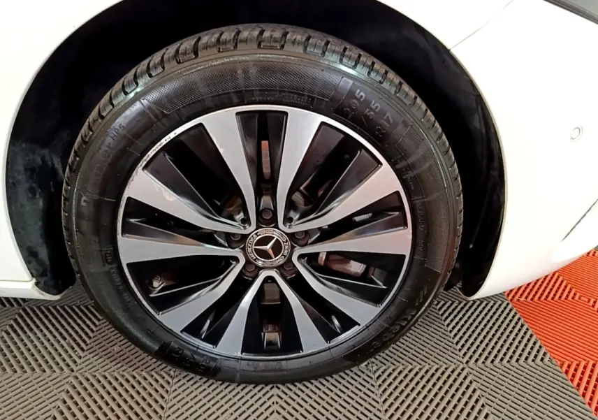 Gros plan sur la roue avant droite d’une Mercedes Classe A blanche, jante alliage bicolore au design moderne.