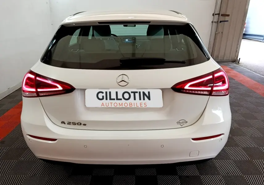 Vue arrière d'une Mercedes Classe A 250 e Business Line blanche avec feux LED allumés dans un garage.