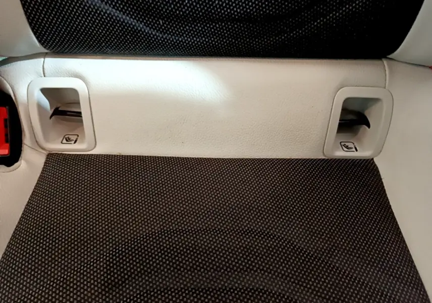 Gros plan sur la banquette arrière en tissu gris foncé avec appuie-têtes et ceintures intégrées d'une Mercedes Classe A blanche.