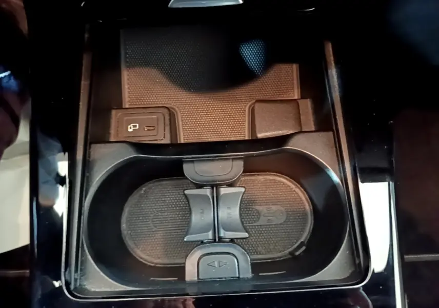 Gros plan sur la console centrale noire de la Mercedes Classe A 250 e, avec porte-gobelets et prise USB visible.