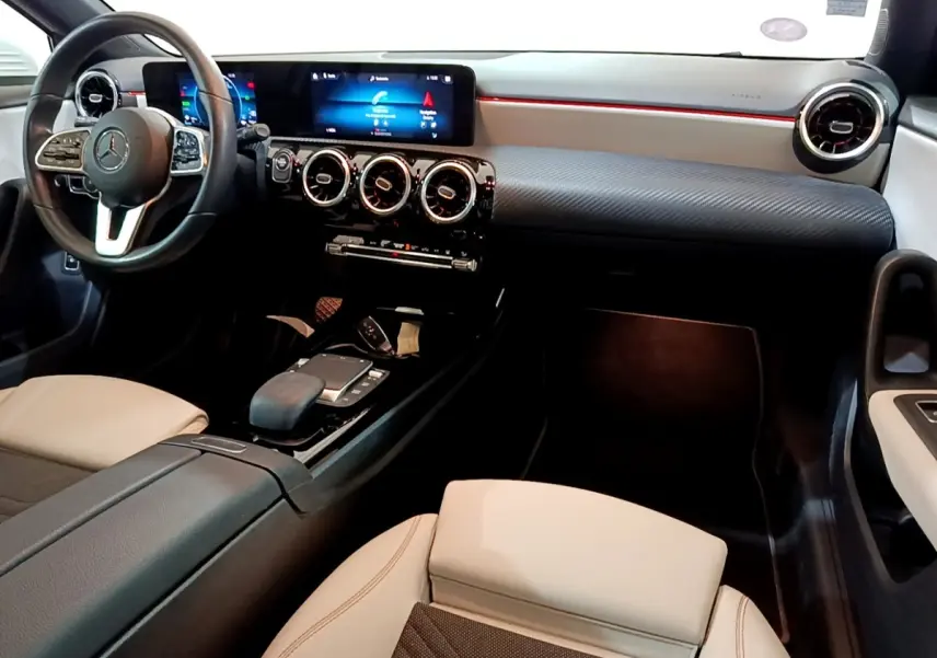 Vue intérieure côté conducteur de la Mercedes Classe A blanche, avec tableau de bord numérique et volant cuir multifonctions.
