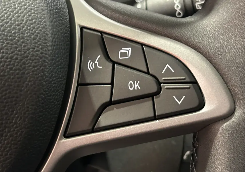 Gros plan sur les commandes multifonctions noires du volant du Dacia Jogger 2026, finition gris schiste métal.