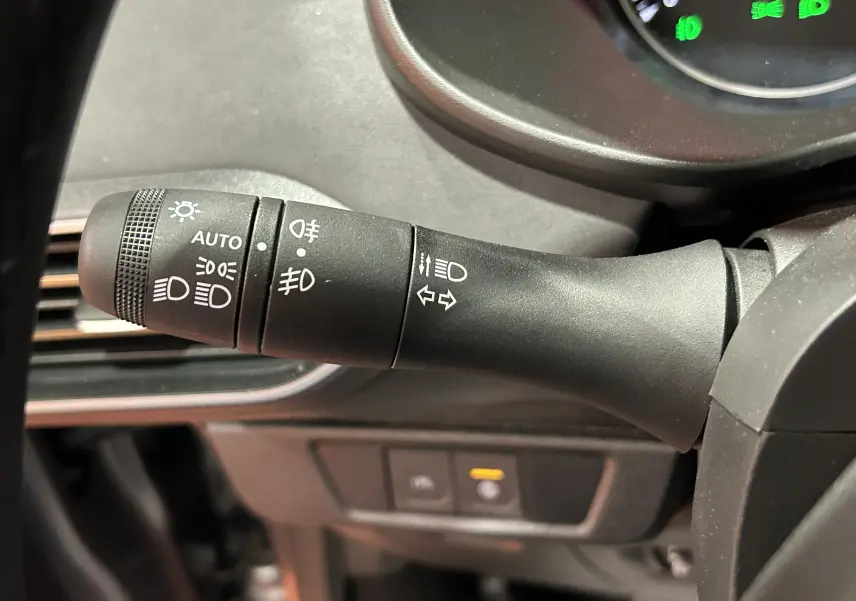 Gros plan sur la commande des phares et clignotants à gauche du volant dans un Dacia Jogger gris schiste métal 2026.