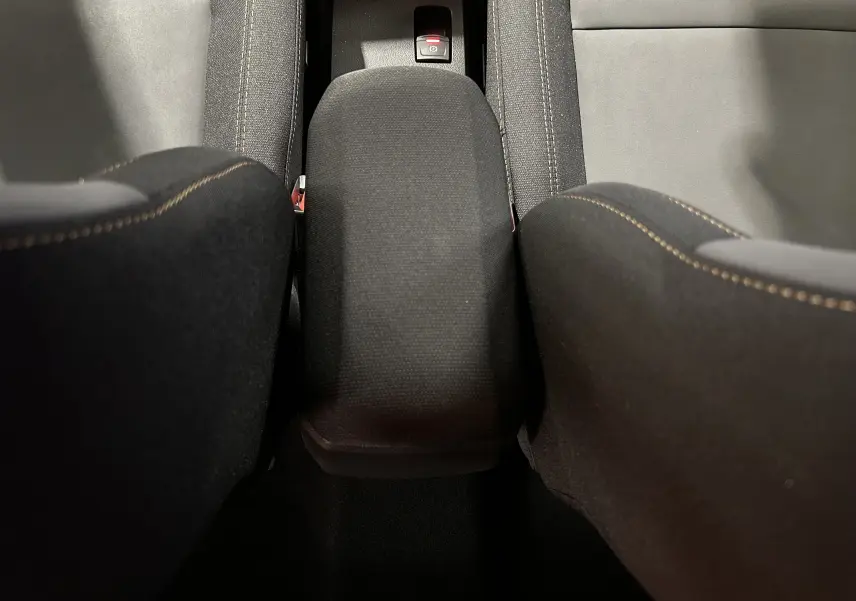 Vue plongeante sur l'accoudoir central noir et les sièges avant en tissu noir du Dacia Jogger 2026.