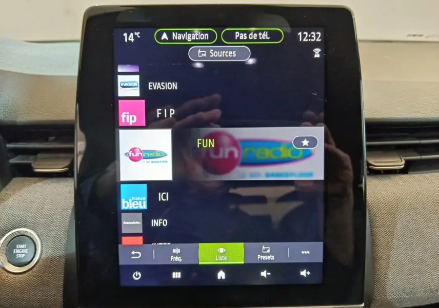 Écran tactile central de la Renault Clio Techno TCe 90 2024 affichant les stations radio avec bouton démarrage visible à gauche.