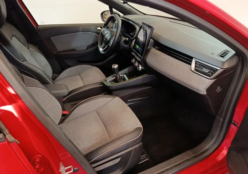 Vue intérieure côté conducteur de la Renault Clio rouge 2024, avec tableau de bord moderne et écran tactile vertical.