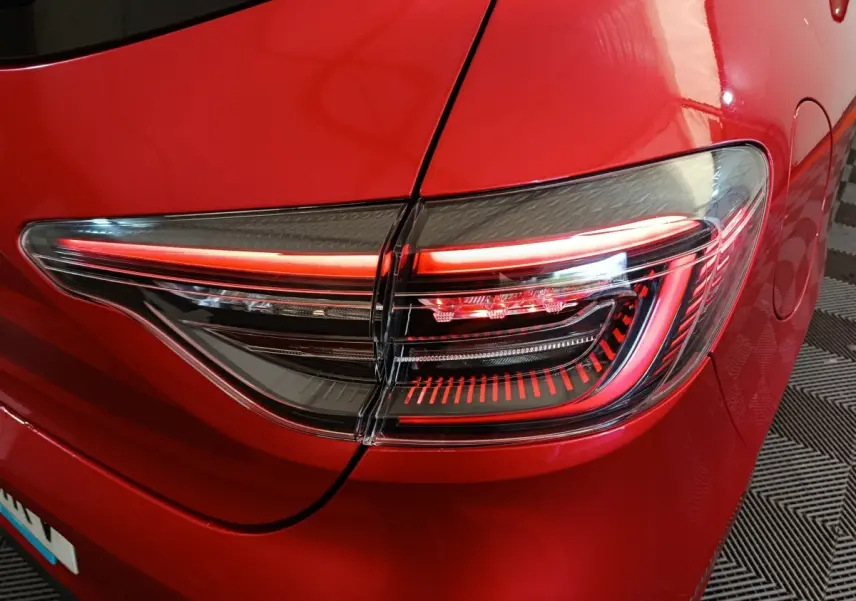 Gros plan sur le feu arrière droit rouge vif d’une Renault Clio 2024 Techno TCe 90, détails LED visibles.
