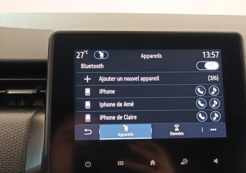 Écran tactile central de la Renault Clio Business blanc, affichant la connexion Bluetooth avec plusieurs appareils iPhone.