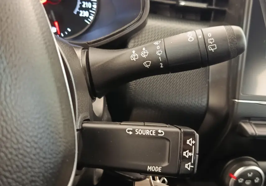Gros plan sur la commande multifonction gauche du tableau de bord d’une Renault Clio blanche, intérieur noir.