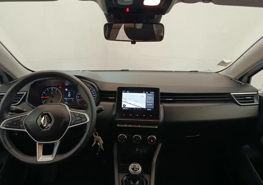 Vue intérieure avant du tableau de bord noir de la Renault Clio Business TCe 100 GPL avec volant multifonctions et écran tactile central.