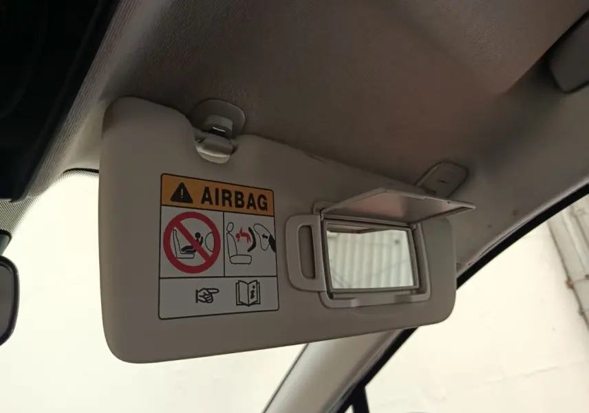Pare-soleil intérieur beige avec miroir de courtoisie ouvert dans une Renault Clio blanche, vue côté conducteur.
