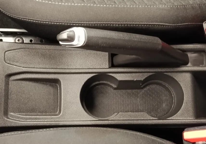 Gros plan sur le frein à main et porte-gobelets noirs au centre de la console d'une Renault Clio Business blanche de 2021.