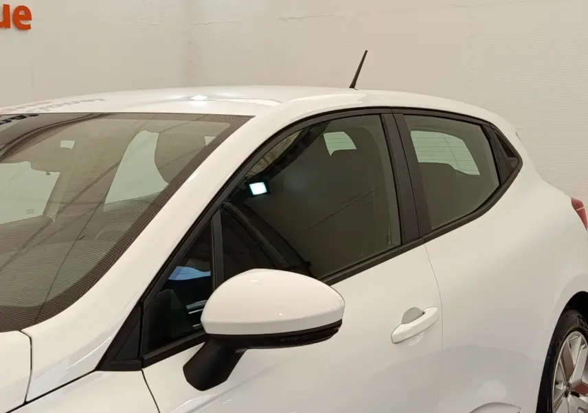 Vue côté gauche avant d'une Renault Clio Business blanche, avec rétroviseur blanc et vitres teintées.