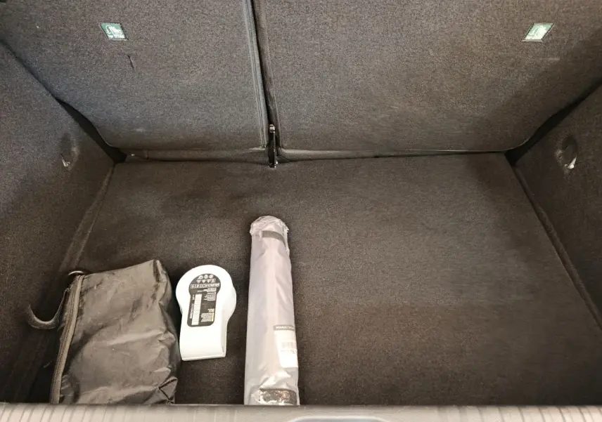 Coffre ouvert d'une Renault Clio Business blanc, vue de dessus avec accessoires de sécurité posés au sol.
