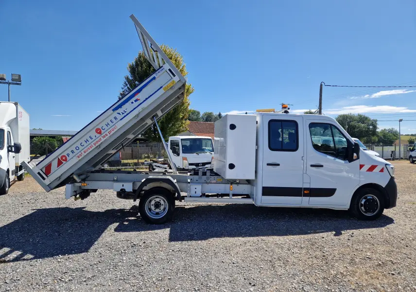 Vue latérale droite d’un Renault Master blanc avec benne relevée et coffre latéral sur châssis double cabine.