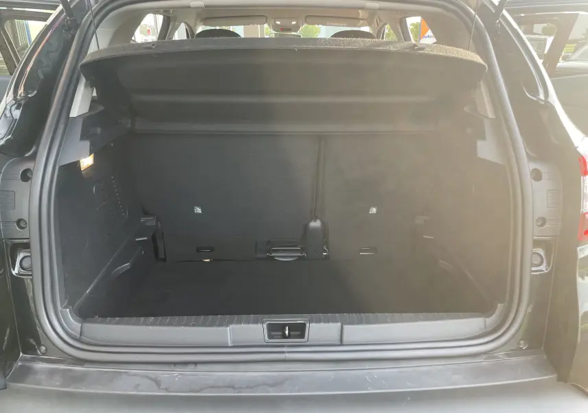 Coffre ouvert vu de l'arrière d'un Renault Captur noir étoile, montrant un espace de chargement propre et spacieux.