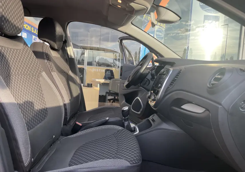 Intérieur avant du Renault Captur noir étoile, sièges tissu gris beige et tableau de bord avec console centrale visible.