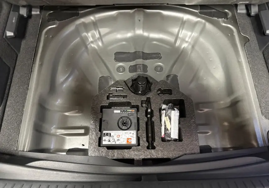 Coffre ouvert en vue plongeante du CUPRA Formentor noir minuit, montrant le rangement pour roue de secours et kit de réparation.