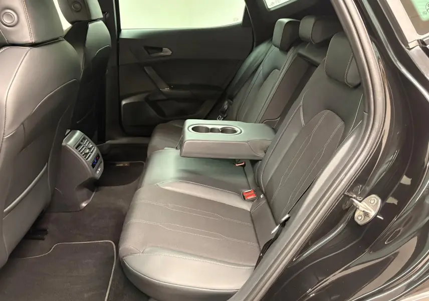 Vue intérieure côté droit des sièges arrière en cuir noir du CUPRA Formentor 2024 avec accoudoir central et porte-gobelets.