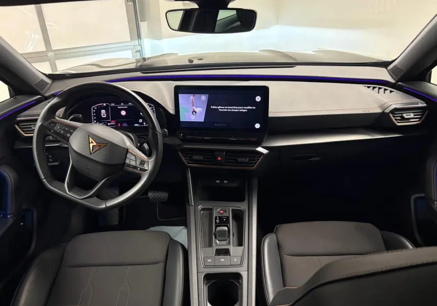 Vue intérieure avant du CUPRA Formentor 1.5 TSI 2024, tableau de bord noir avec éclairage d’ambiance violet et écran tactile central.