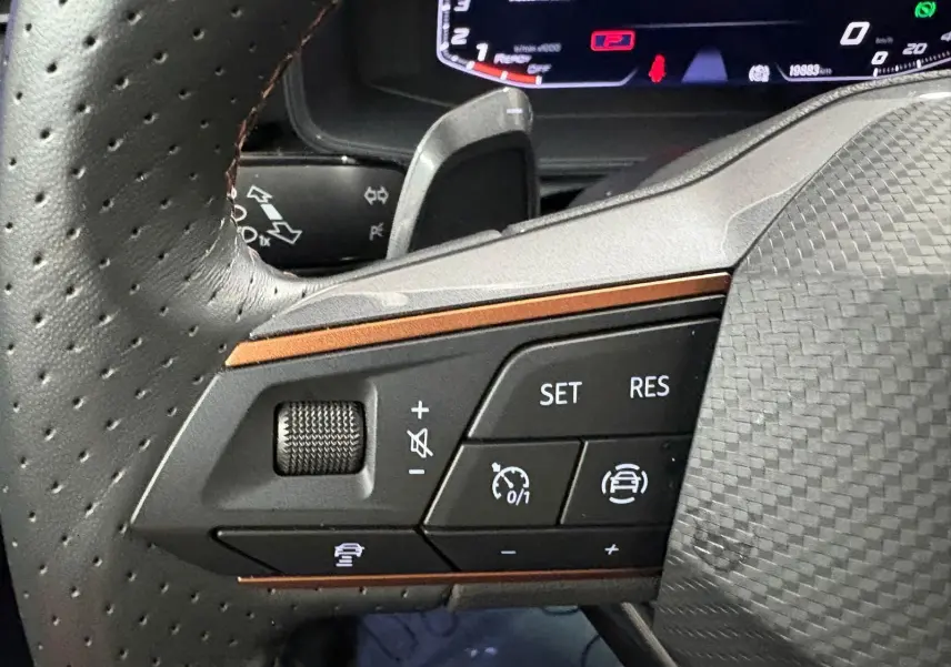 Gros plan sur les commandes gauche du volant perforé du CUPRA Formentor 2024, finition noire avec détails cuivrés.