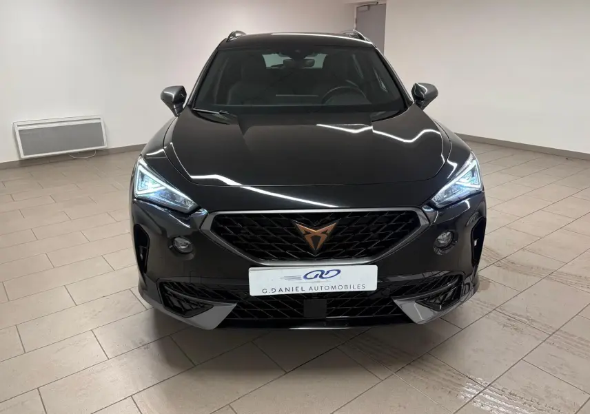 Vue avant d'une CUPRA Formentor 1.5 TSI 150 DSG7 en noir minuit avec phares LED allumés dans un intérieur neutre.