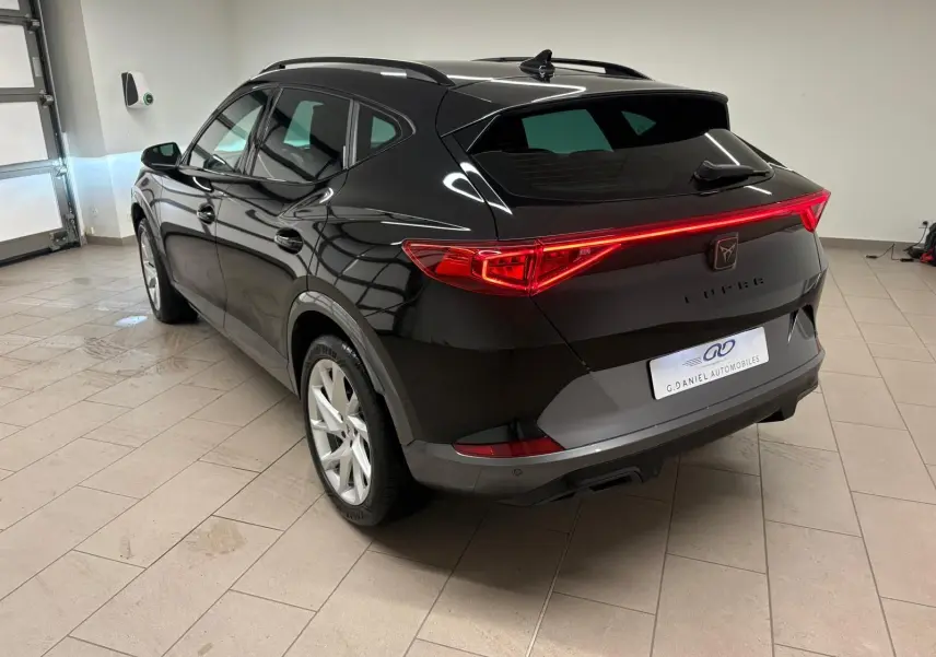 Vue 3/4 arrière droite du CUPRA Formentor noir minuit 2024, avec feux arrière allumés et jantes argentées.