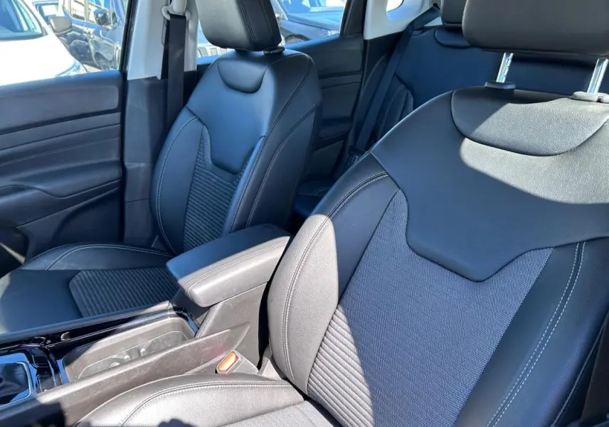 Vue rapprochée des sièges avant en cuir noir du Jeep Compass 2024 avec accoudoir central et finitions soignées.