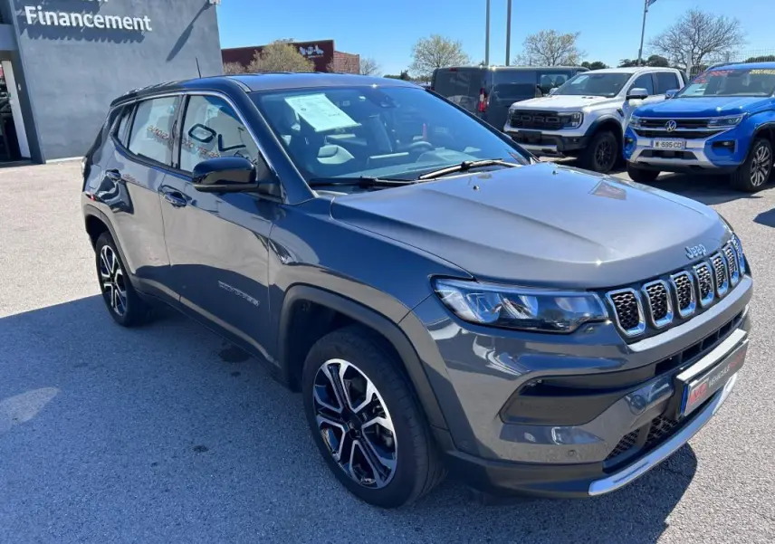 Jeep Compass gris vu en 3/4 avant droit, mettant en valeur ses jantes alliage 18 pouces et ses phares LED.