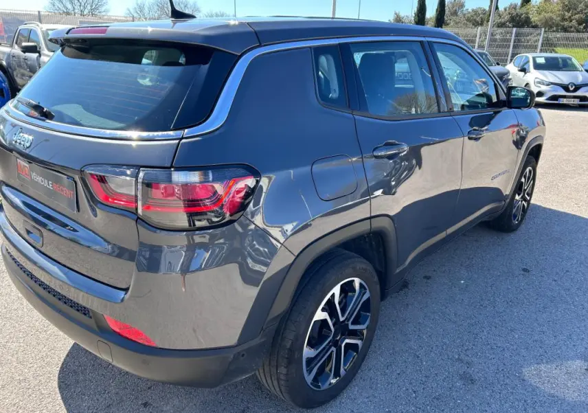 Vue 3/4 arrière droite d'un Jeep Compass gris 2024 avec jantes alliage 18 pouces et feux arrière LED.