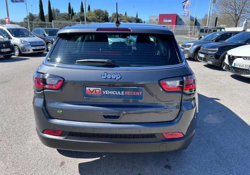 Vue arrière d'un Jeep Compass gris 2024 avec logo Jeep et plaque VÉHICULE RÉCENT visible en extérieur.