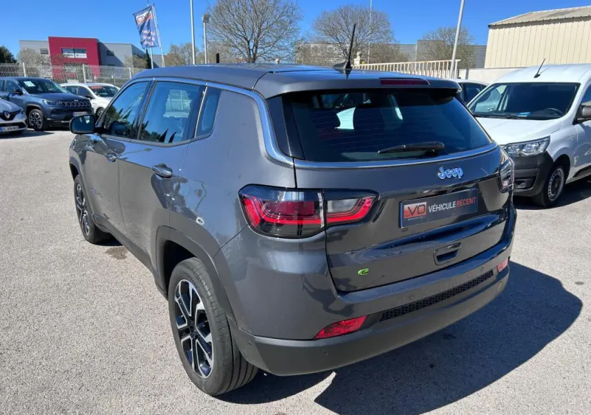 Jeep Compass gris 3/4 arrière droit, jantes alliage 18 pouces, feux arrière LED et badge e-Hybrid visible.