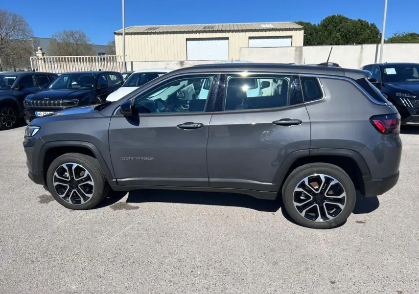 Vue latérale droite d'un Jeep Compass gris 2024 avec jantes alliage 18 pouces et toit noir contrasté.