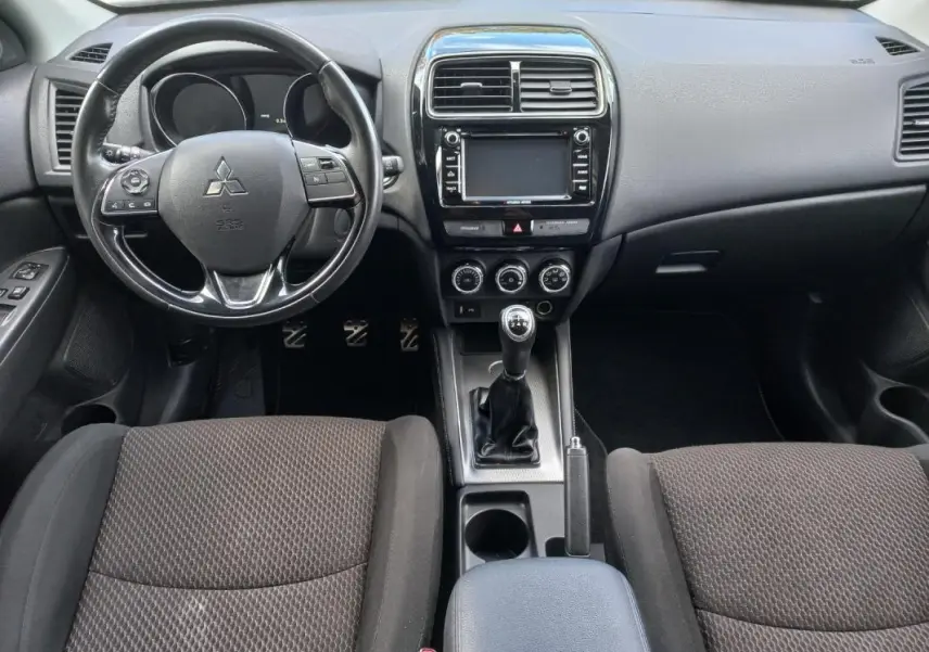 Vue intérieure frontale du Mitsubishi ASX 2020 noir, montrant le volant, la console centrale avec boîte manuelle et accoudoir central.