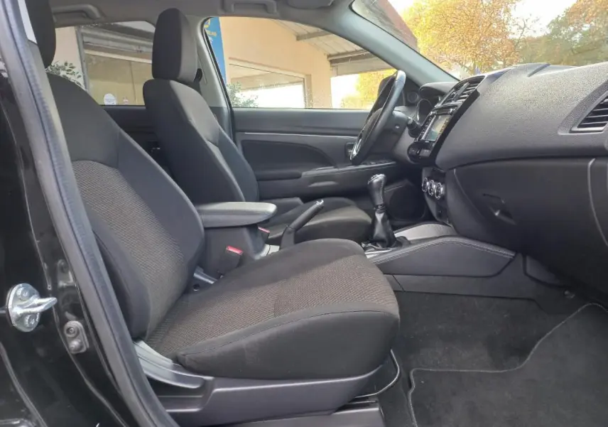 Intérieur avant côté gauche du Mitsubishi ASX noir 2020, montrant sièges, accoudoir central et tableau de bord.
