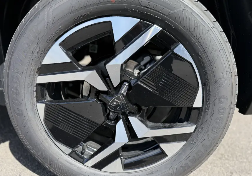 Gros plan sur la jante noire et argentée d’une Peugeot 2008 Hybrid 145ch avec pneu Goodyear visible.