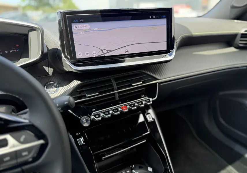 Intérieur du Peugeot 2008 Hybrid 145ch GT, vue centrée sur la console avec écran tactile et commandes piano noires brillantes.