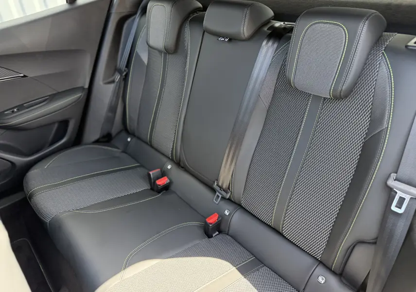Vue intérieure du siège arrière droit du Peugeot 2008 Hybrid 145ch GT, tissu noir avec surpiqûres vertes contrastantes.
