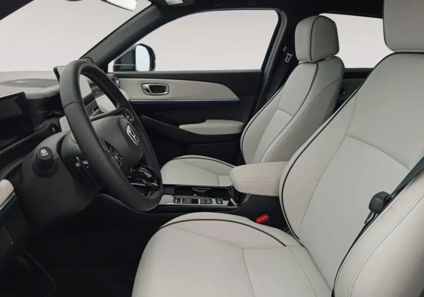 Intérieur clair du Honda e:Ny1 204 ch Advance 2025, vue côté conducteur avec sièges en cuir clair et volant noir.