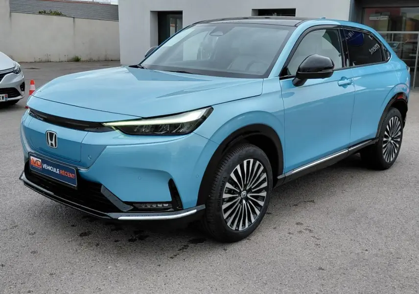 Vue 3/4 avant droite d'un Honda e:Ny1 204 ch Advance bleu électrique avec jantes stylisées et toit noir.