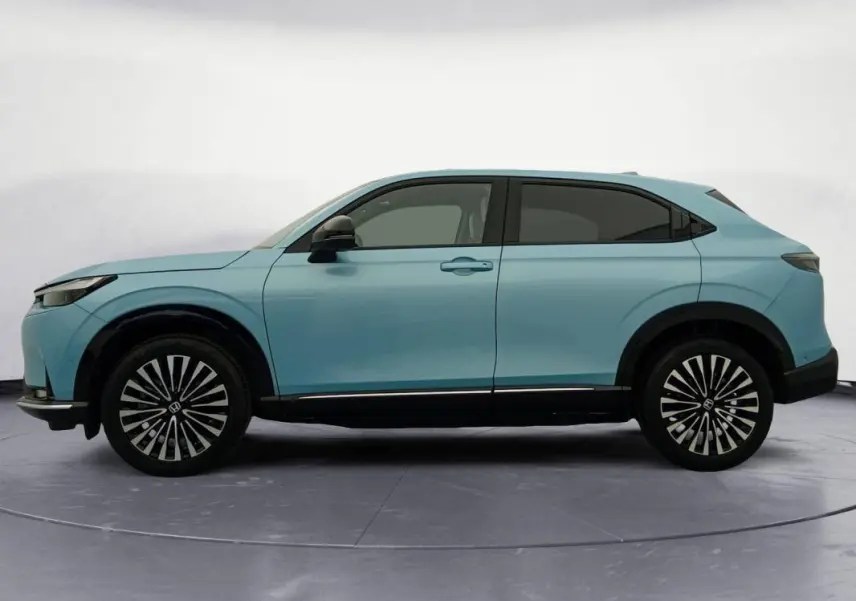 Vue latérale gauche du Honda e:Ny1 204 ch Advance 2025 en bleu, avec jantes distinctives bicolores et lignes épurées.