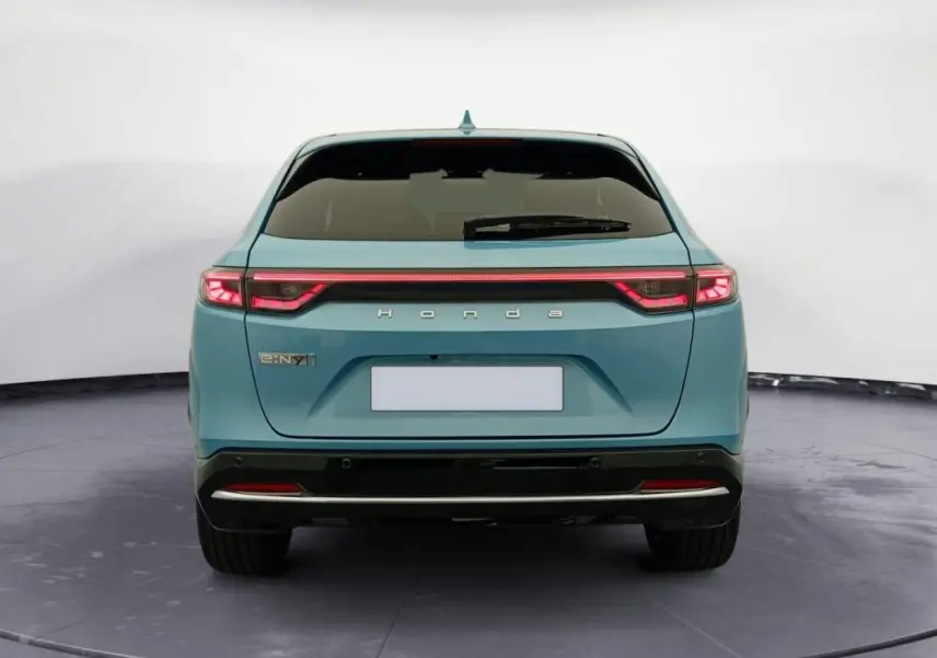 Vue arrière d'une Honda e:Ny1 Advance 204 ch 2025 en bleu avec feux arrière LED reliés par une bande lumineuse.