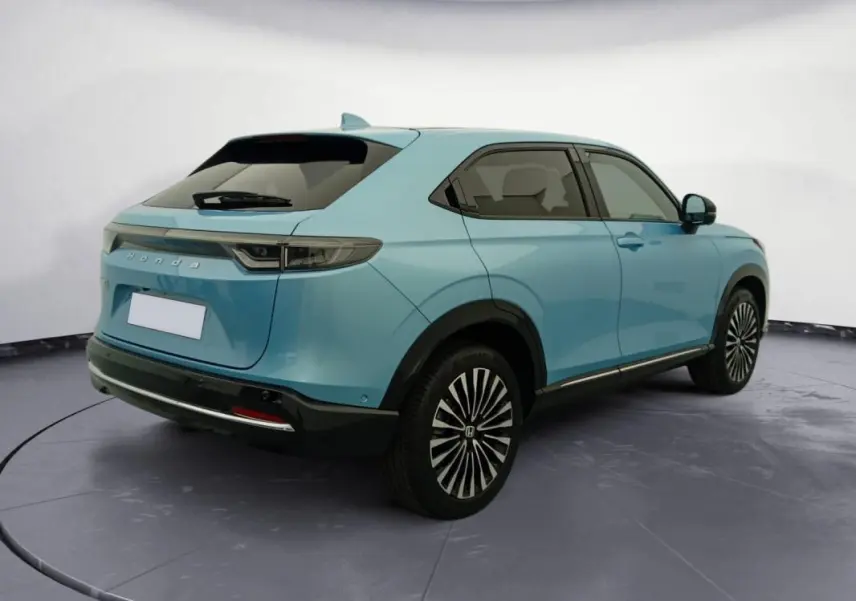 Honda e:Ny1 204 ch Advance 2025 bleu électrique, vue 3/4 arrière droit, jantes stylisées et lignes épurées.